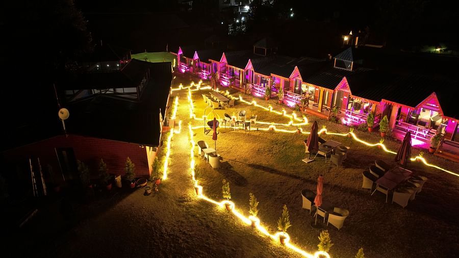 Sol Glow Resort, Nainital Nainital Night view of a set of cottages in an inverted V shape, with colorful lights glowing up the frontyard and common lawns